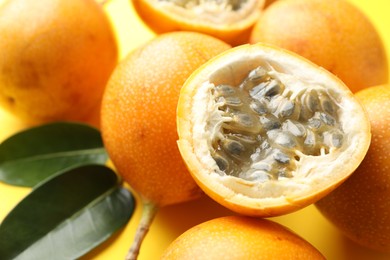 Photo of Ripe passion fruits and leaves on yellow background, closeup