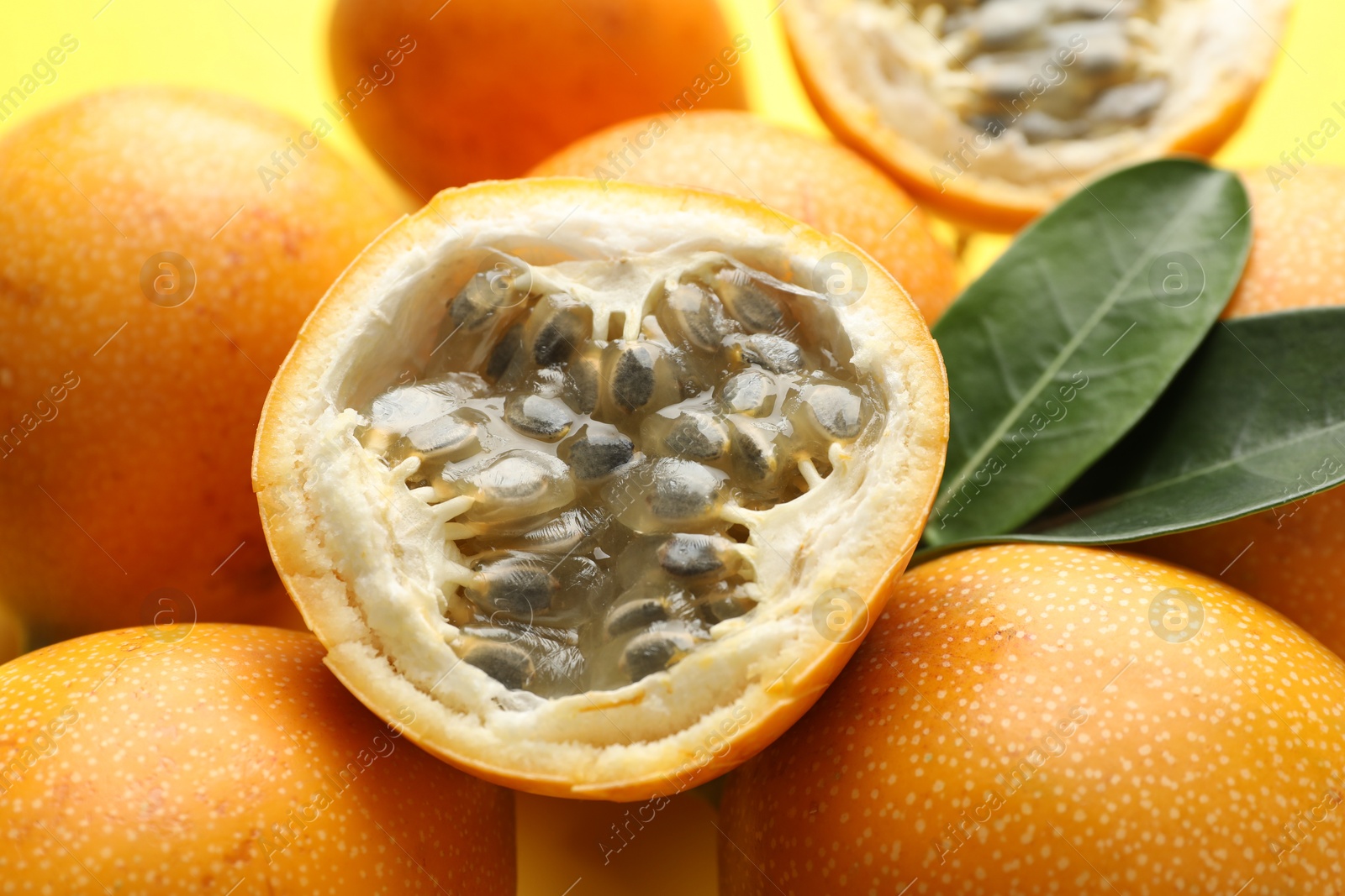 Ripe passion fruits and leaves on yellow background, closeup Photo of Ripe passion fruits and leaves on yellow background, closeup
