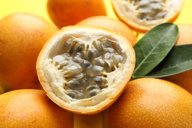 Photo of Ripe passion fruits and leaves on yellow background, closeup
