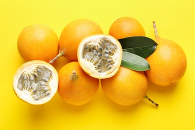 Photo of Ripe passion fruits and leaves on yellow background, flat lay
