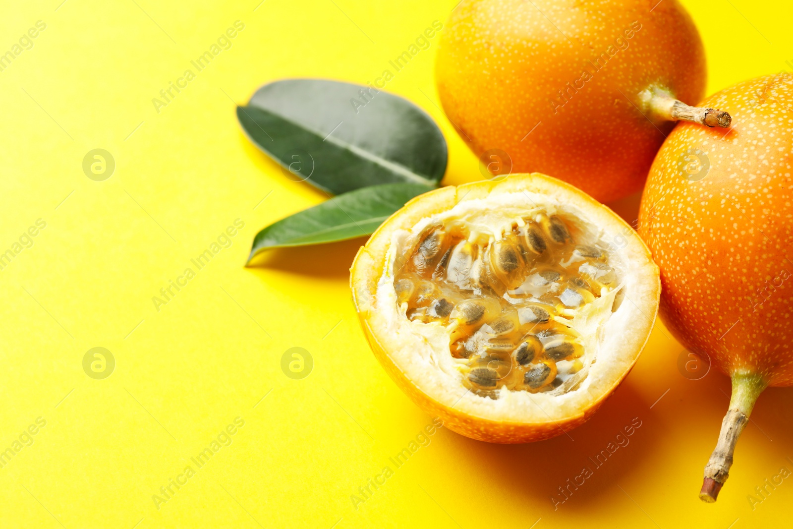 Ripe passion fruits and leaves on yellow background, closeup. Space for text Photo of Ripe passion fruits and leaves on yellow background, closeup. Space for text