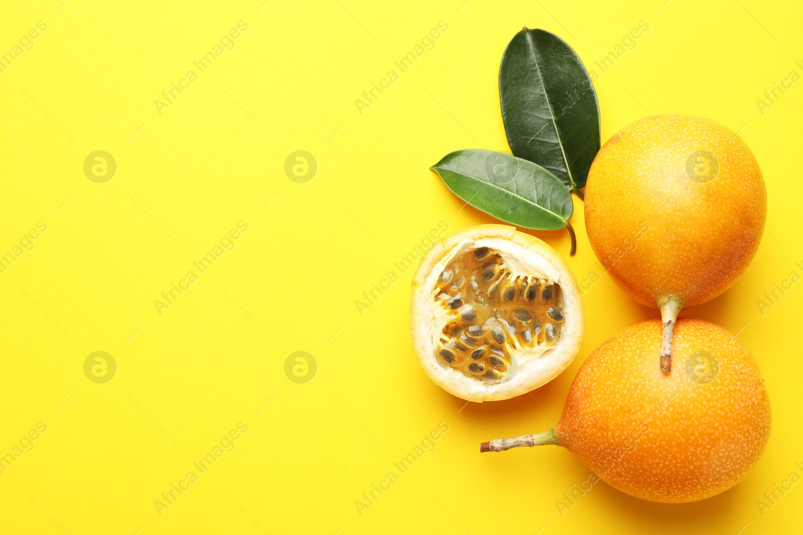 Ripe passion fruits and leaves on yellow background, flat lay. Space for text Photo of Ripe passion fruits and leaves on yellow background, flat lay. Space for text