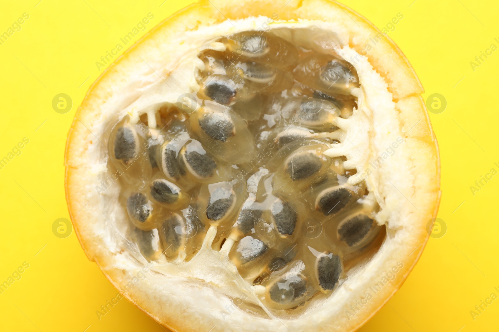 Piece of ripe passion fruit on yellow background, closeup Photo of Piece of ripe passion fruit on yellow background, closeup