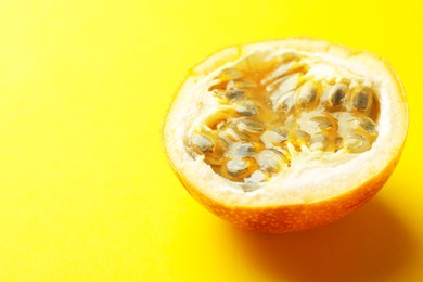 Photo of Piece of ripe passion fruit on yellow background, closeup. Space for text