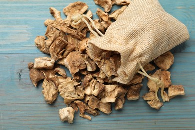 Photo of Pieces of dry chicory roots and sack on blue wooden table, top view