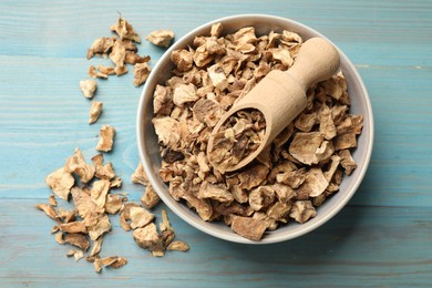Photo of Pieces of dry chicory roots and scoop in bowl on blue wooden table, top view