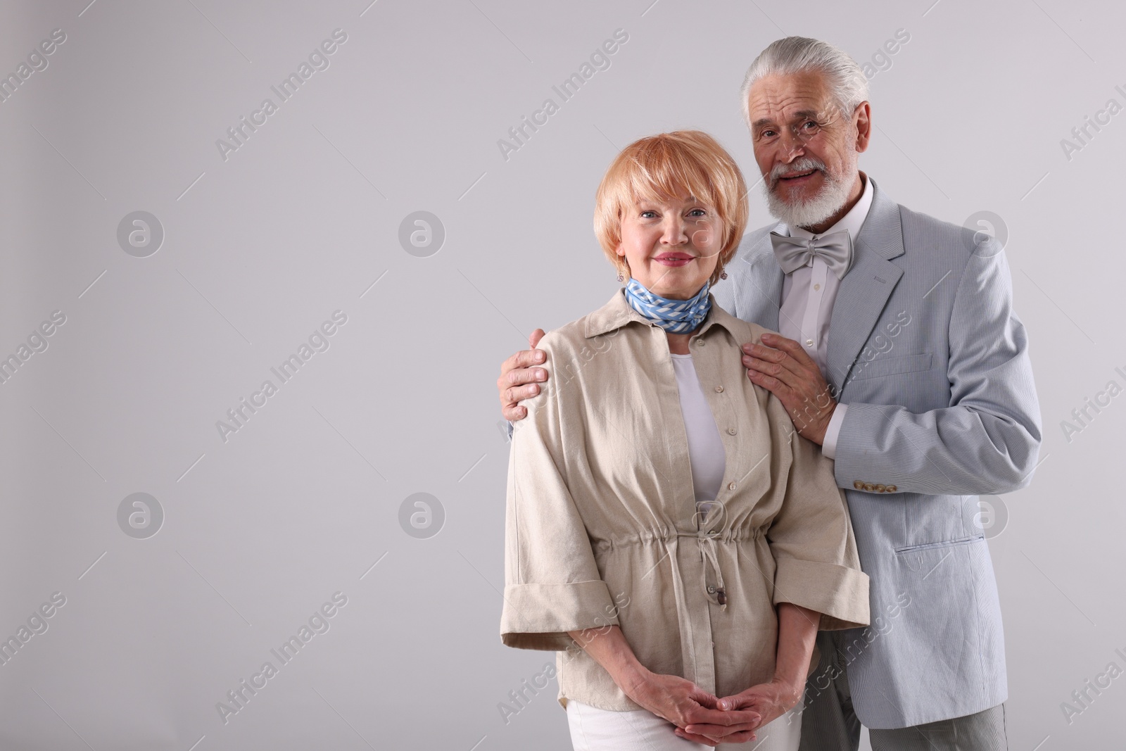 Lovely senior couple together on light grey background, space for text Photo of Lovely senior couple together on light grey background, space for text