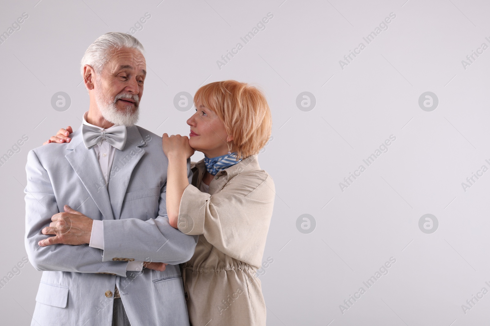Lovely senior couple together on light grey background, space for text Photo of Lovely senior couple together on light grey background, space for text