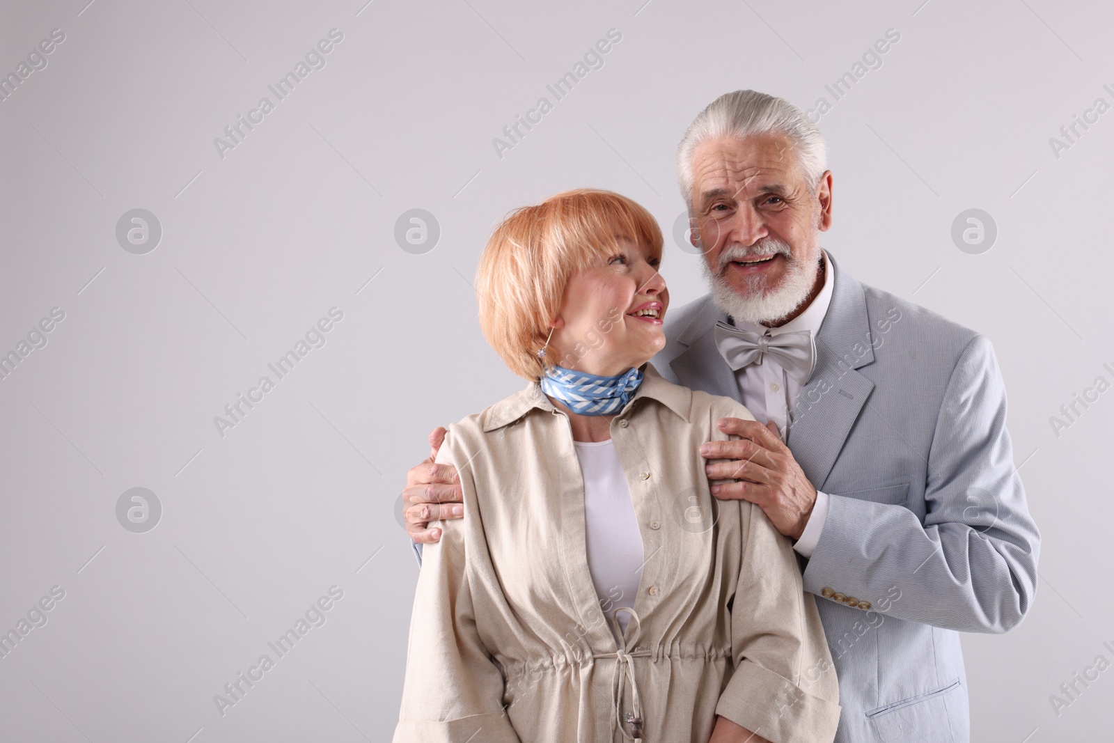 Lovely senior couple together on light grey background, space for text Photo of Lovely senior couple together on light grey background, space for text