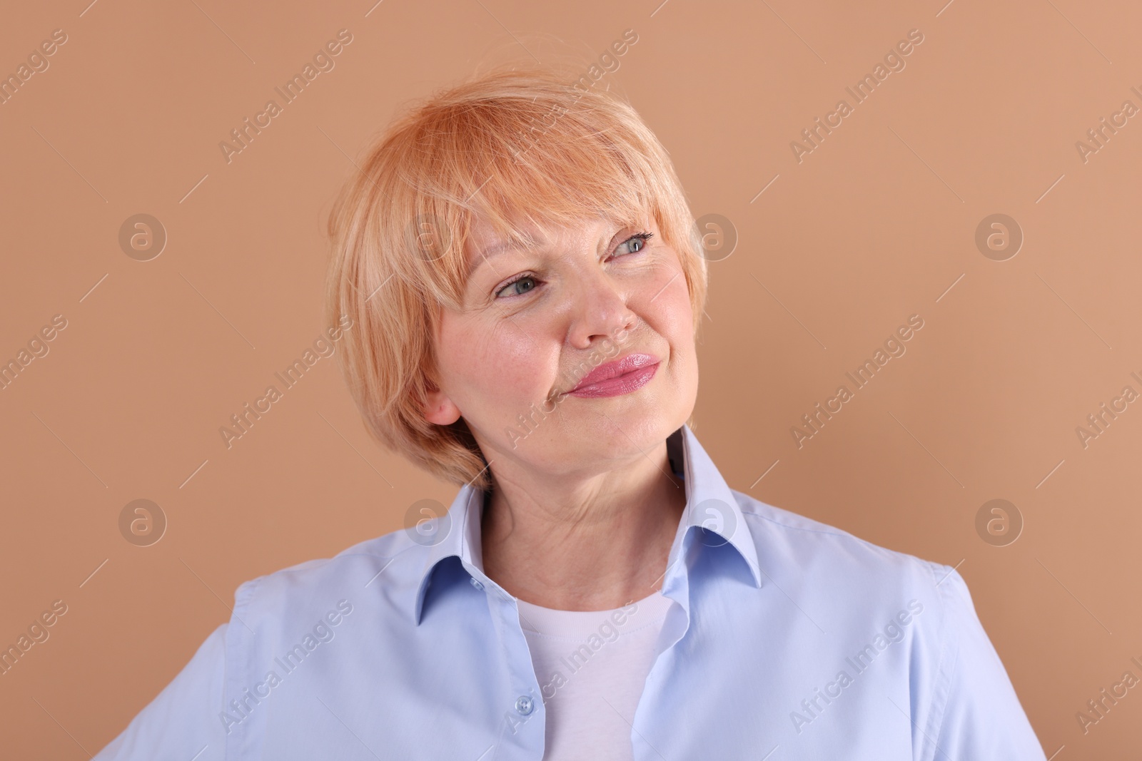 Portrait of senior woman on light brown background Photo of Portrait of senior woman on light brown background