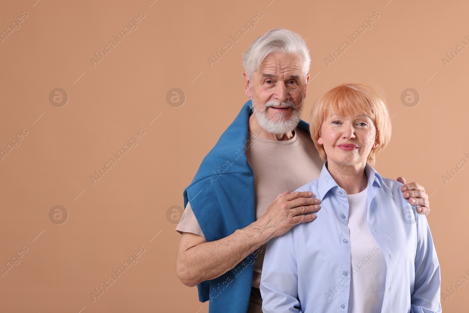 Lovely senior couple together on light brown background, space for text Photo of Lovely senior couple together on light brown background, space for text