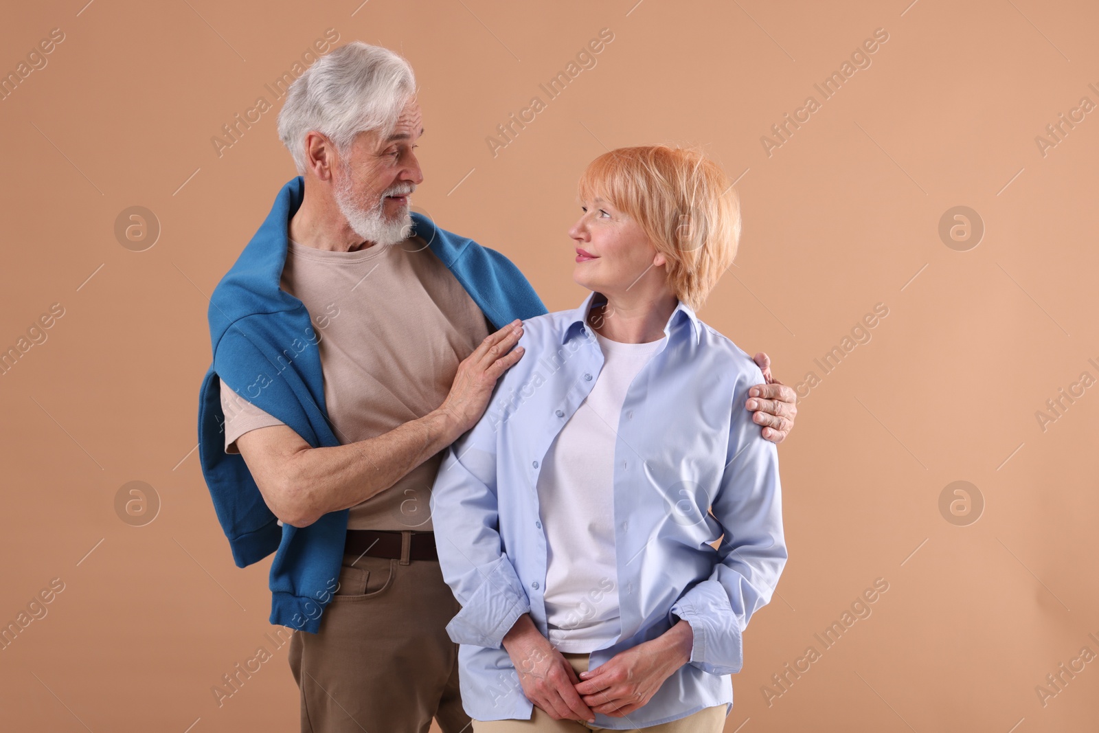 Lovely senior couple together on light brown background Photo of Lovely senior couple together on light brown background