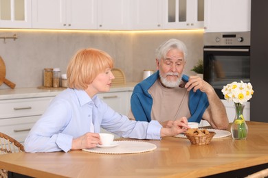 Photo of Lovely senior couple having breakfast together at wooden table in kitchen
