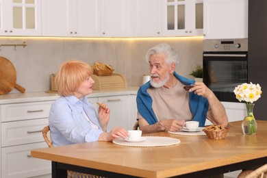 Photo of Lovely senior couple having breakfast together at wooden table in kitchen