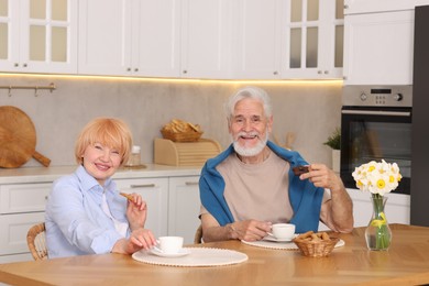 Photo of Lovely senior couple having breakfast together at wooden table in kitchen