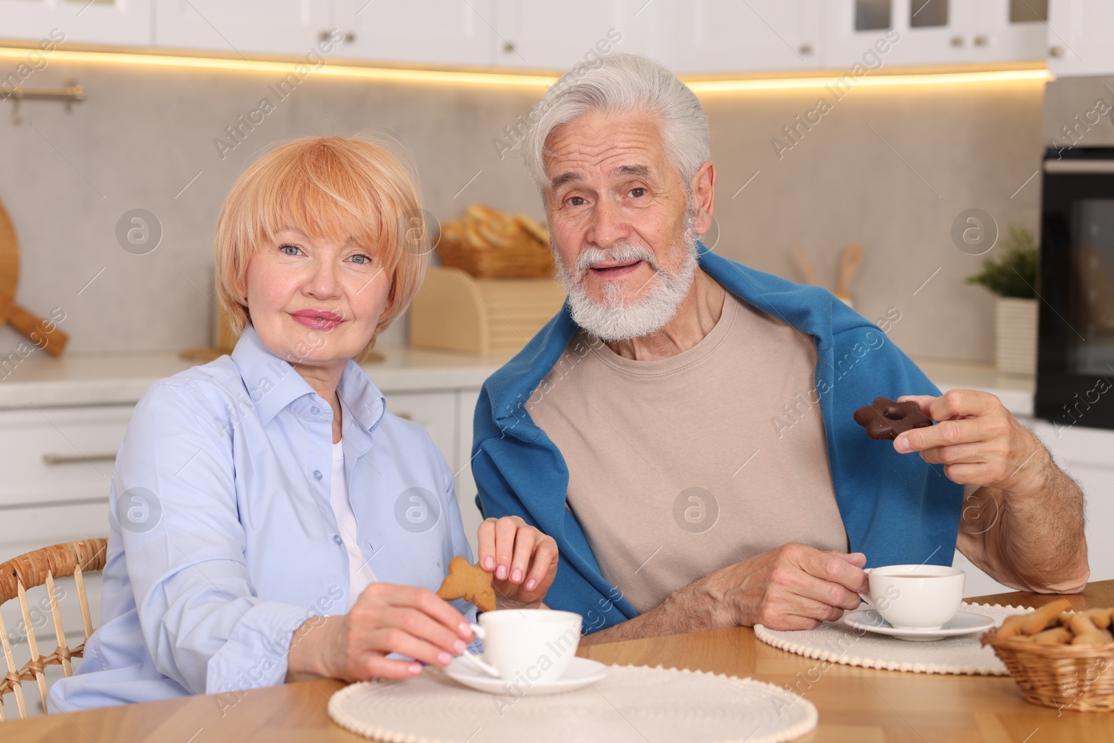 Lovely senior couple having breakfast together at wooden table in kitchen Photo of Lovely senior couple having breakfast together at wooden table in kitchen