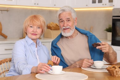 Photo of Lovely senior couple having breakfast together at wooden table in kitchen