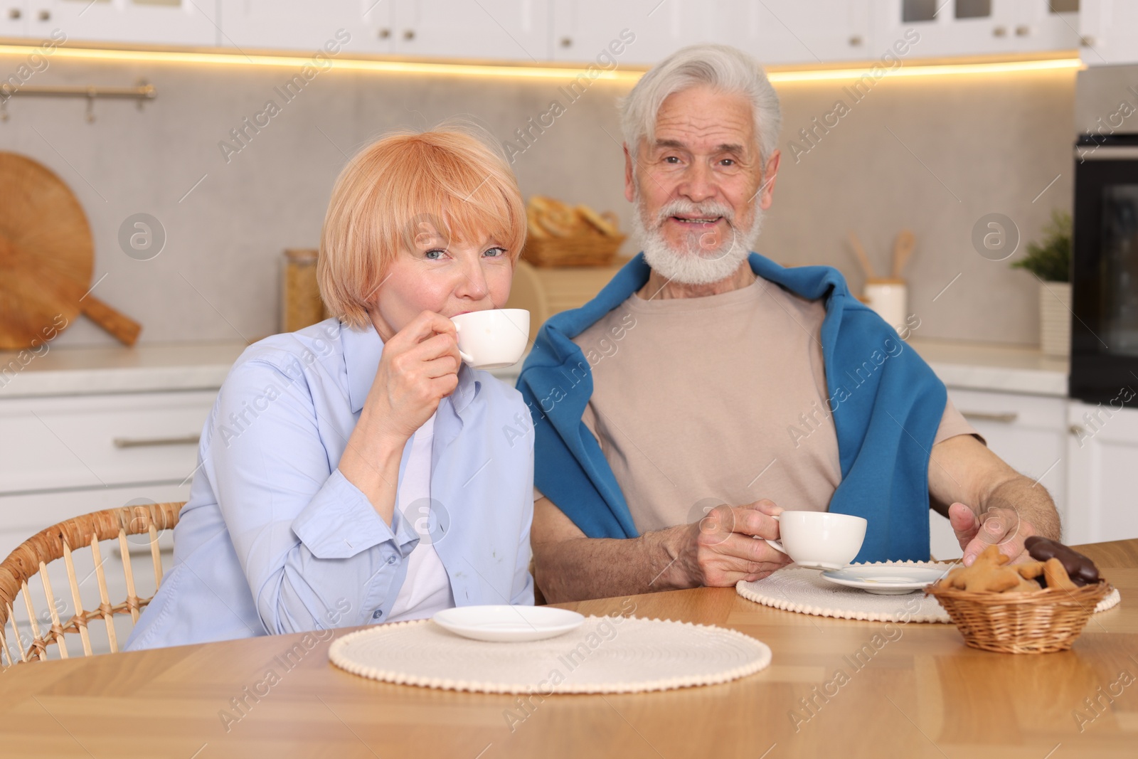 Lovely senior couple having breakfast together at wooden table in kitchen Photo of Lovely senior couple having breakfast together at wooden table in kitchen