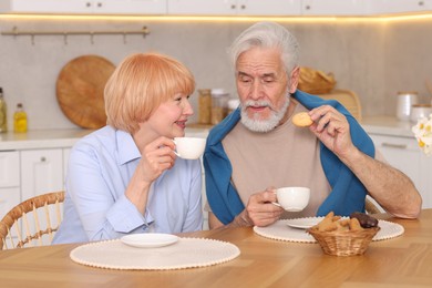 Photo of Lovely senior couple having breakfast together at wooden table in kitchen