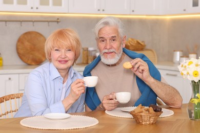 Photo of Lovely senior couple having breakfast together at wooden table in kitchen