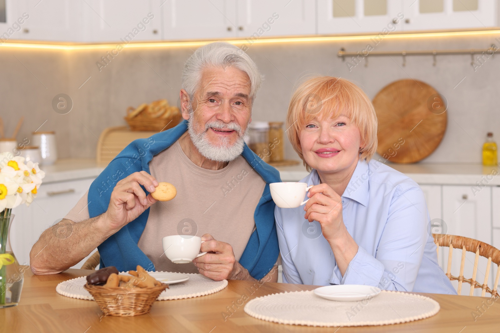 Lovely senior couple having breakfast together at wooden table in kitchen Photo of Lovely senior couple having breakfast together at wooden table in kitchen
