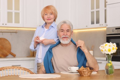 Photo of Lovely senior couple having breakfast together at wooden table in kitchen