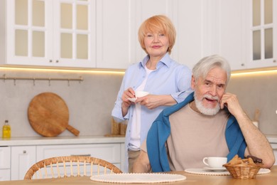 Photo of Lovely senior couple having breakfast together at wooden table in kitchen