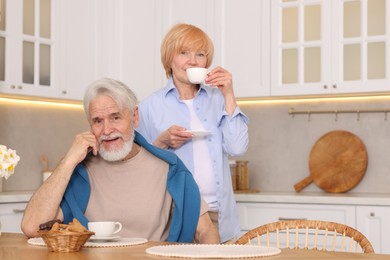 Photo of Lovely senior couple having breakfast together at wooden table in kitchen