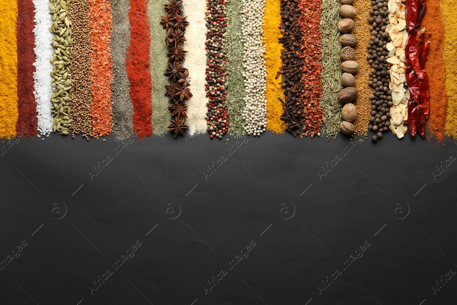 Many different spices on black table, flat lay. Space for text Photo of Many different spices on black table, flat lay. Space for text