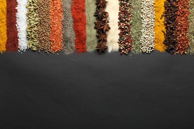 Photo of Many different spices on black table, flat lay. Space for text