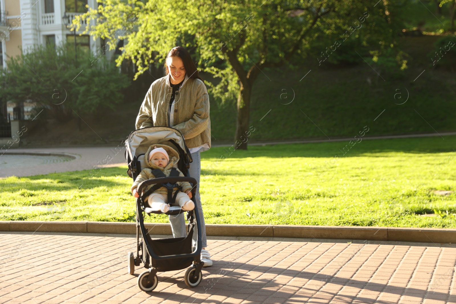Mother walking with her baby in stroller at park on sunny day. Space for text Photo of Mother walking with her baby in stroller at park on sunny day. Space for text