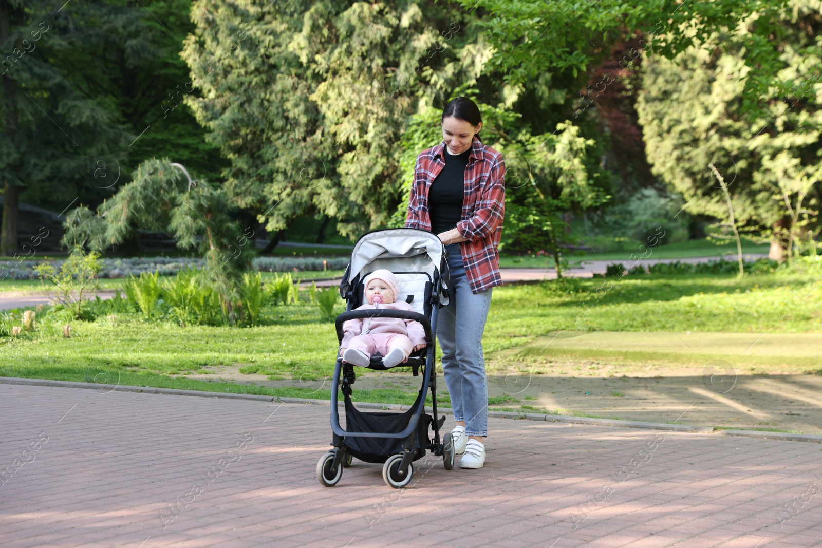 Mother walking with her baby in stroller at park Photo of Mother walking with her baby in stroller at park