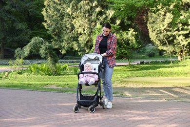 Photo of Mother walking with her baby in stroller at park