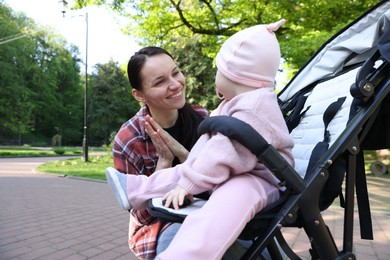 Photo of Mother playing with her cute baby in stroller at park