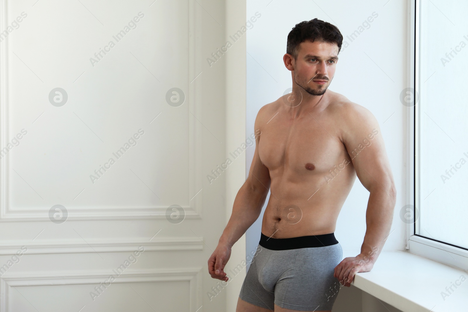 Young man in stylish light grey underwear near white wall indoors. Space for text Photo of Young man in stylish light grey underwear near white wall indoors. Space for text