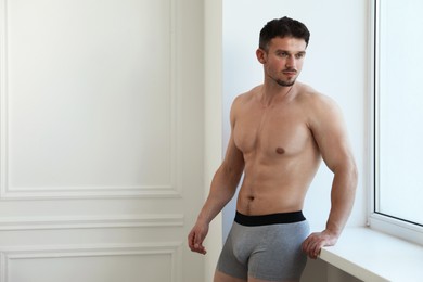 Photo of Young man in stylish light grey underwear near white wall indoors. Space for text