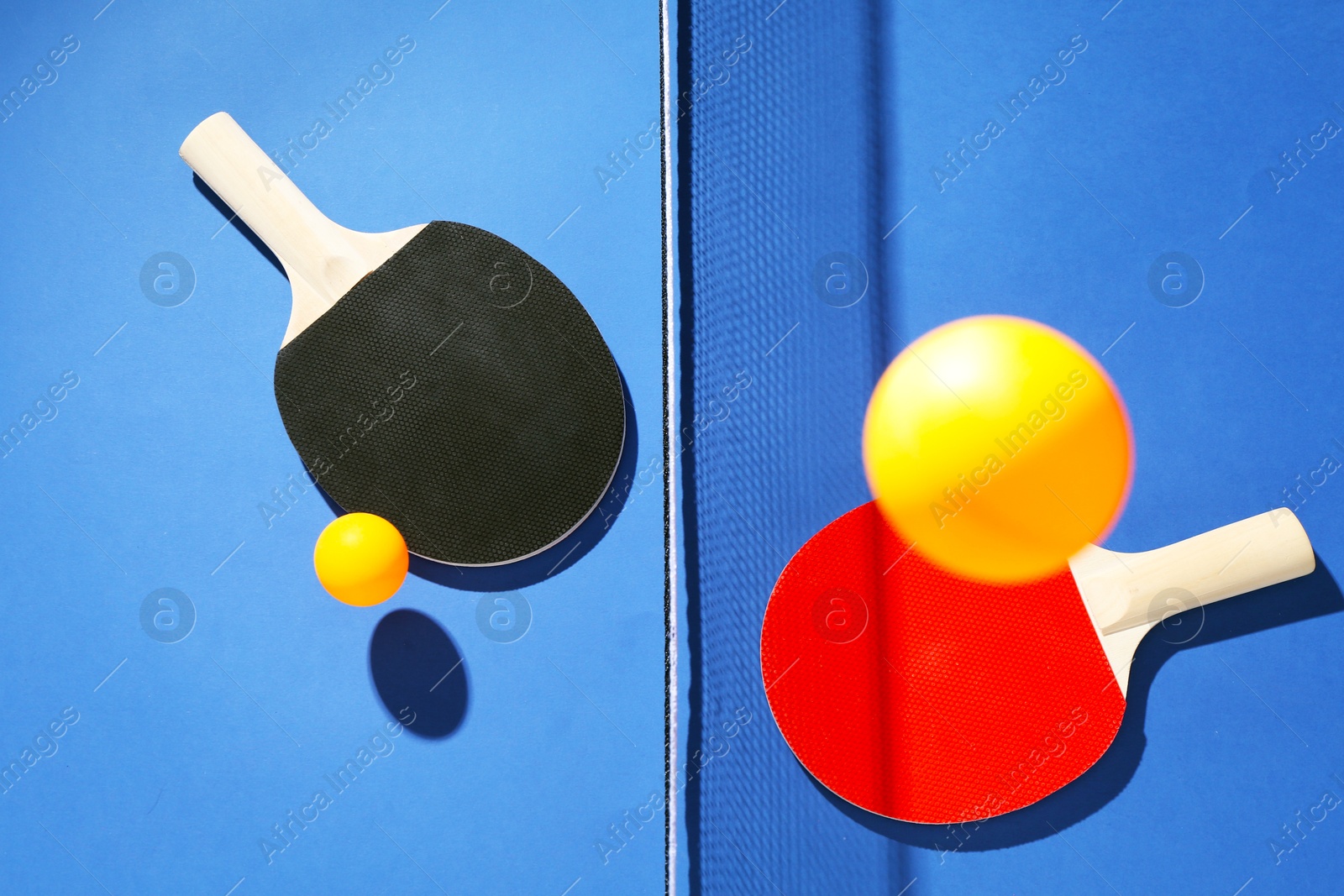 Ping pong rackets, balls and net on blue background, flat lay Photo of Ping pong rackets, balls and net on blue background, flat lay