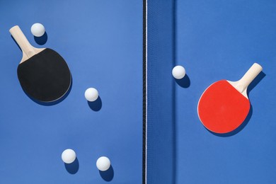 Photo of Ping pong rackets, balls and net on blue background, flat lay