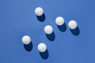 Photo of Many ping pong balls on blue background, flat lay