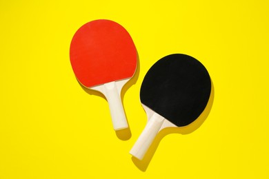 Photo of Ping pong rackets on yellow background, top view