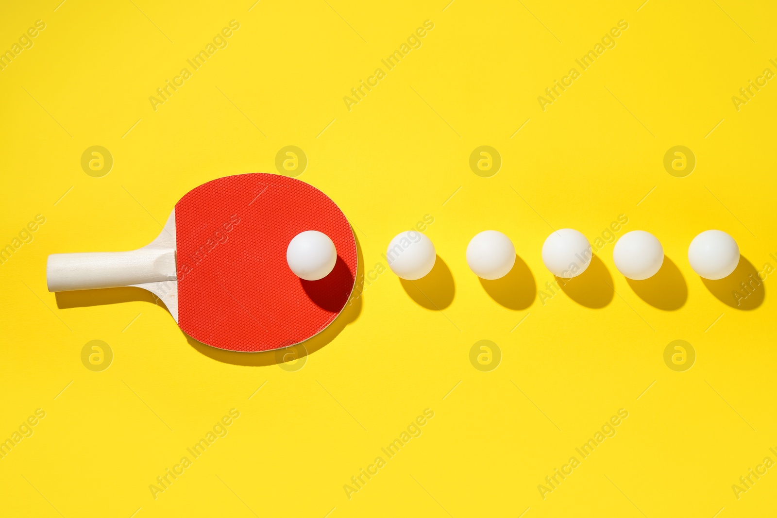 Ping pong racket and balls on yellow background, flat lay Photo of Ping pong racket and balls on yellow background, flat lay