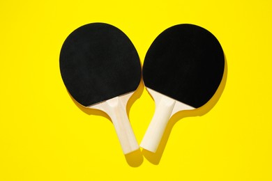 Photo of Ping pong rackets on yellow background, top view