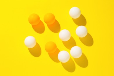 Photo of Ping pong balls on yellow background, flat lay