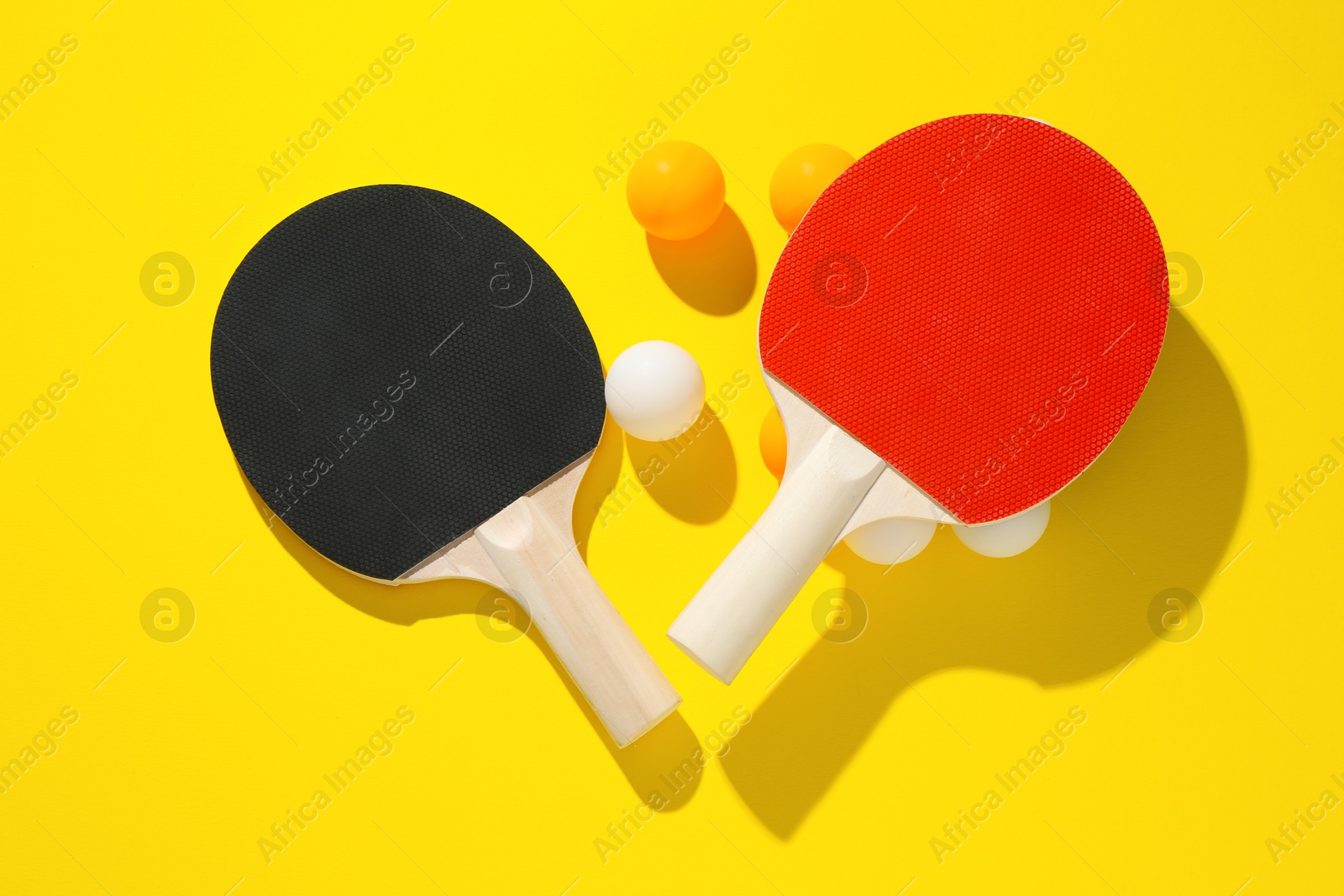 Ping pong rackets and balls on yellow background, flat lay Photo of Ping pong rackets and balls on yellow background, flat lay