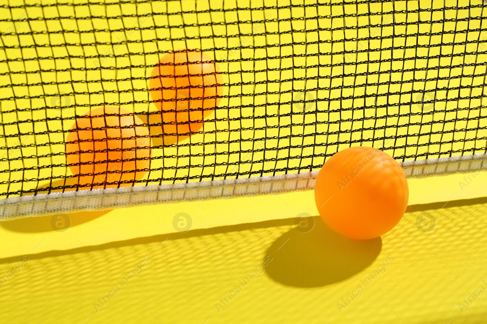 Ping pong balls and net on yellow background, closeup Photo of Ping pong balls and net on yellow background, closeup