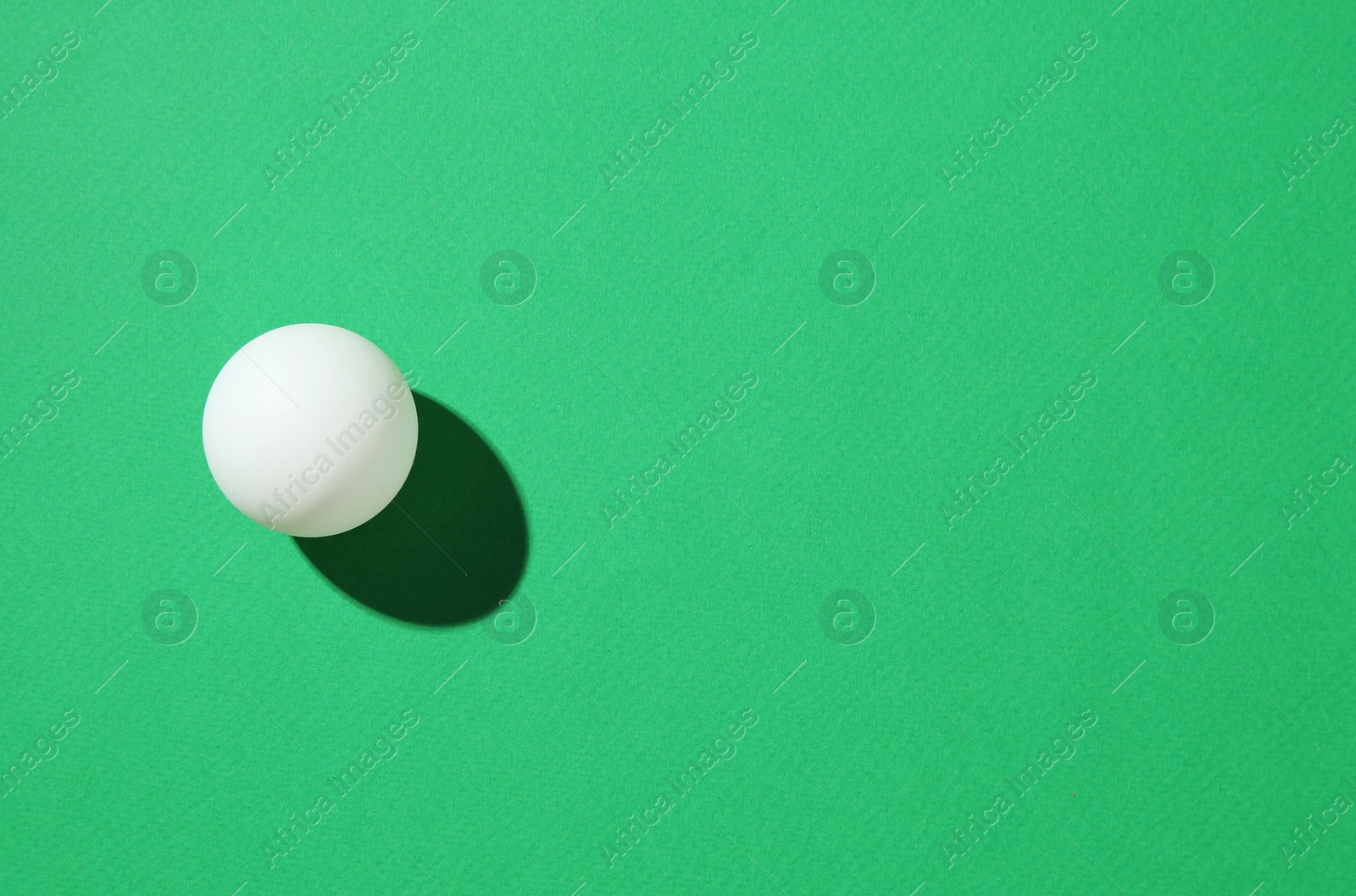 One ping pong ball on green background, top view. Space for text Photo of One ping pong ball on green background, top view. Space for text