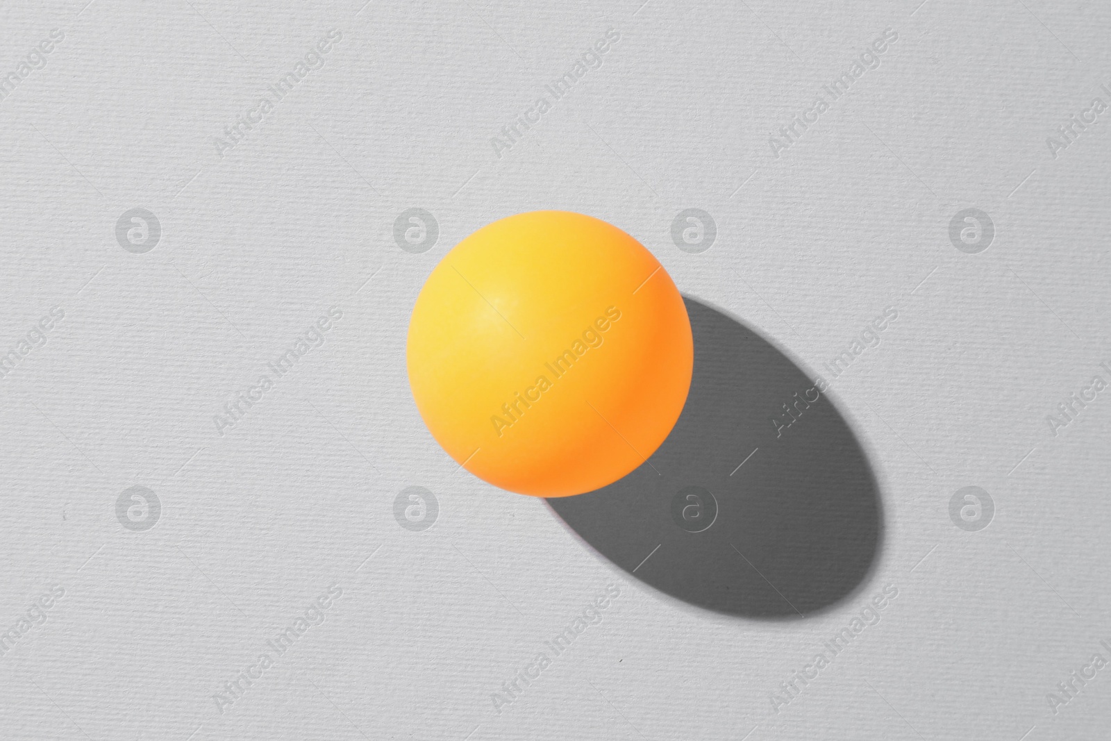 One ping pong ball on light background, top view Photo of One ping pong ball on light background, top view