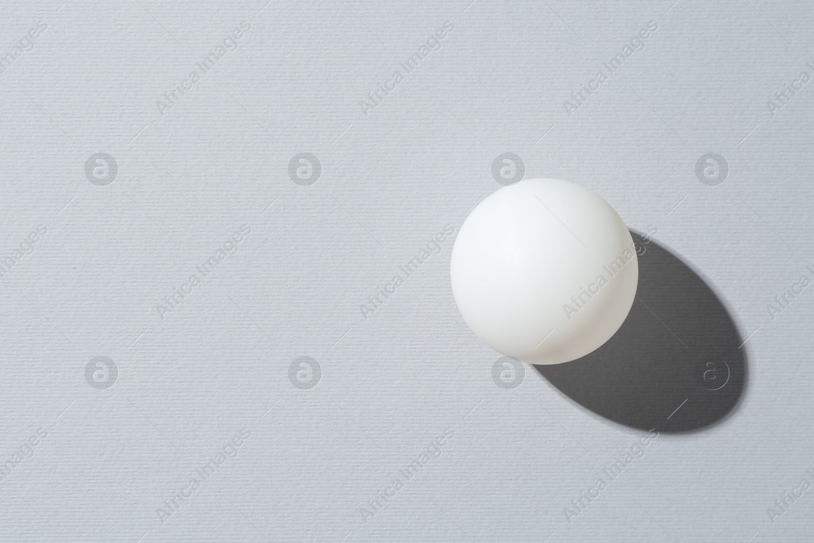 One ping pong ball on light background, top view. Space for text Photo of One ping pong ball on light background, top view. Space for text