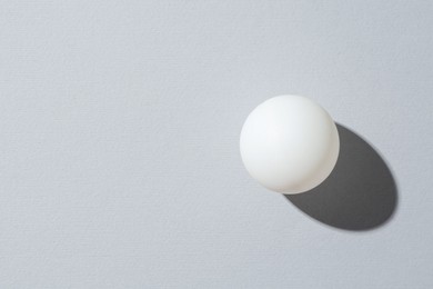 Photo of One ping pong ball on light background, top view. Space for text