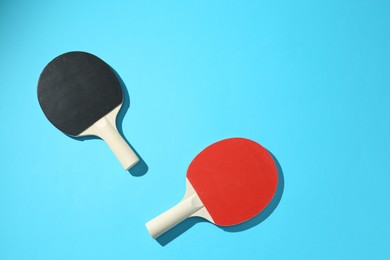 Photo of Ping pong rackets on blue background, top view. Space for text